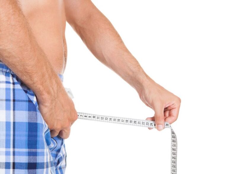 Mann misst seinen Penis mit einem Zentimeter